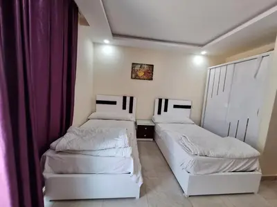 two beds in a small room with purple curtains at ميراج باى in Hurghada