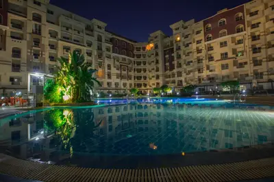 a large pool in front of a building at night at Florenza khamsin Resort in Hurghada