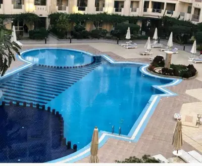 a swimming pool in a courtyard with chairs and umbrellas at Florenza Resort in Hurghada