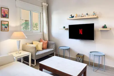 a living room with a couch and a tv on a wall at The 2BDR Warmhearted Waterside Apt in Hurghada