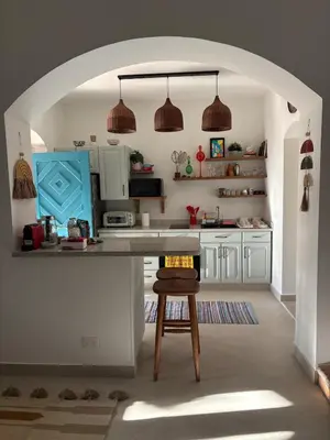 a kitchen with white cabinets and a table with a stool at Cozy 1BR in the Heart of Gouna in Hurghada