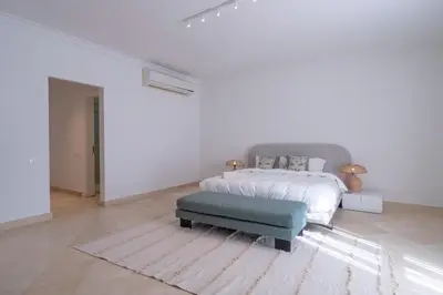 a white bedroom with a bed and a green ottoman at Luxury 5BD Villa with Pool in Hurghada