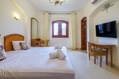 a bedroom with a large white bed and a desk at Serene 4BR Villa • Authentic West Golf in Hurghada