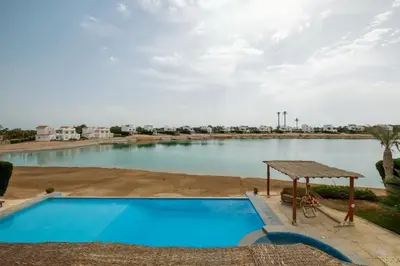 a large swimming pool in front of a body of water at Serene 4BR Villa • Authentic West Golf in Hurghada