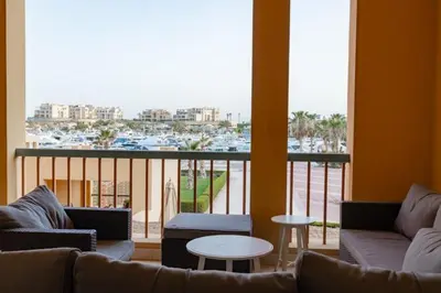 a living room with a couch and a balcony with a harbor at 2BR New Marina Bliss • Cozy Centered Stay in Hurghada