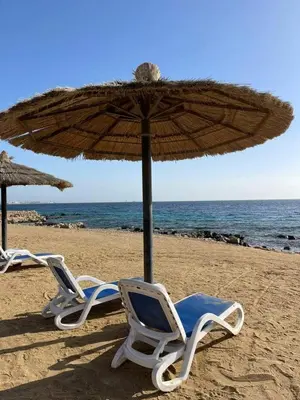 two chairs and an umbrella on a beach at Studio for rent in the view 409 in Hurghada
