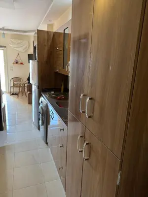 a kitchen with wooden cabinets and a white tile floor at Studio in Casablanca 631 in Hurghada