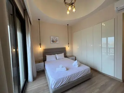 a bedroom with a bed with white sheets and a chandelier at Ancient Sands 4BR • Heated Pool Twin-Villa in Hurghada