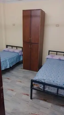 a bedroom with two beds and a wooden cabinet at Luxor downtown in Jazīrat al ‘Awwāmīyah
