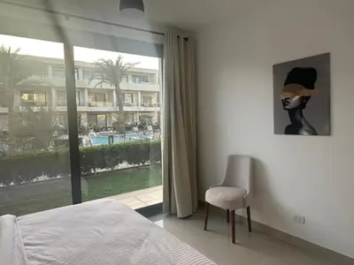a bedroom with a bed and a chair and a window at Hotel apartment G Cribs Hotel in Hurghada