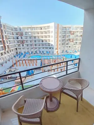 a balcony with two tables and chairs and a pool at Golden tiba resort in Hurghada