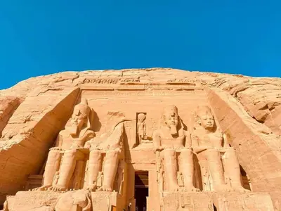 an ancient building with statues on the side of it at Five stars Hotel included Aswan Sightseeing and Abusimble in Nag` el-Ramla
