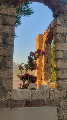 an arch in a brick wall with flowers at House Mountain in Luxor