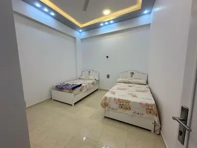 two beds in a room with white walls at Nsma house in Al Aqālitah