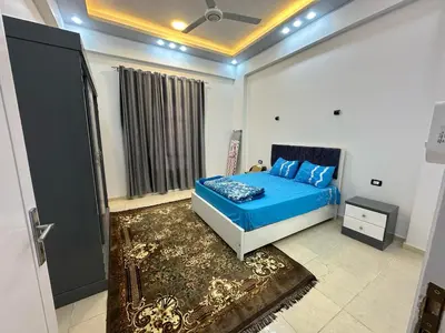 a bedroom with a bed with a blue comforter at Nsma house in Al Aqālitah