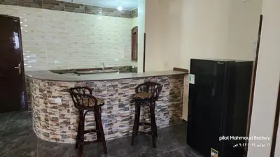 a kitchen with two bar stools and a refrigerator at sky spirit in Luxor