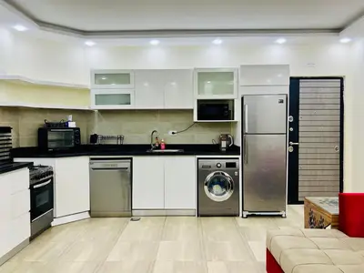 a kitchen with white cabinets and a washer and dryer at Beachfront Bliss - Your Hurghada Escape Awaits in Hurghada
