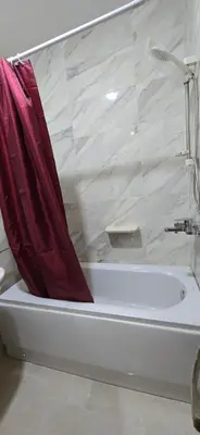 a white bath tub with a red shower curtain at Tiba Golden Marina Bay Hurghada in Hurghada
