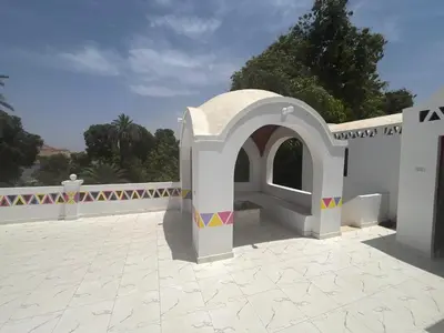 a white building with an arch in a courtyard at Toto Kato in Jazīrat Aswān