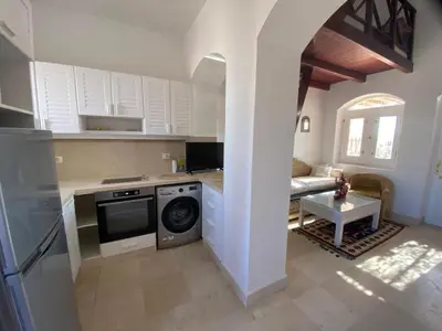 a kitchen with a washing machine and a living room at Apartment at Upper Nubia lagoon El Gouna in Hurghada