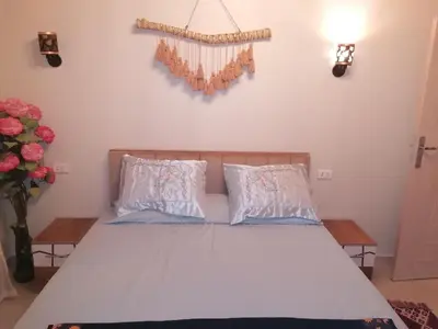 a bed with two pillows and a cross on the wall at 265 Apartment in Hurghada