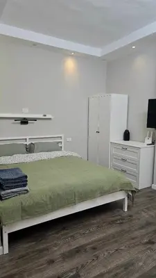 a white bedroom with a bed and a dresser at Florenza Khamsin Lux Apartment in Hurghada