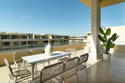 a patio with a table and chairs on a balcony at Cozy getaway in El Gouna with pool & mountain view in Hurghada
