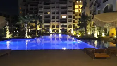 a swimming pool at night with buildings in the background at Amazing Apartment Aldau Heights in Hurghada