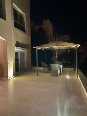 a patio with chairs and an umbrella at night at lovely 2 bedrooms Groundfloor in Hurghada