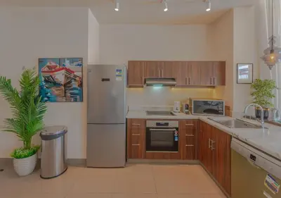 a kitchen with a stainless steel refrigerator and wooden cabinets at 4BR Cyan Dream Villa I Pool Lagoon & Sauna in Hurghada