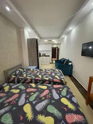 a bedroom with two beds and a couch and a television at Steps from Beach & Near Airport Furnteched, Kitchenette, full APT Free WIFI in Hurghada