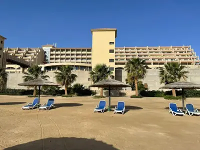 a group of chairs and umbrellas in front of a building at Doplex for rent in the view 18 in Hurghada