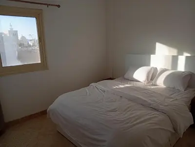 a white bed in a room with a window at Lägenhet i villa med pool i Hurghada-Magawish in Hurghada
