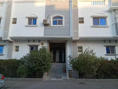 a white building with stairs leading to the front door at Lägenhet i villa med pool i Hurghada-Magawish in Hurghada