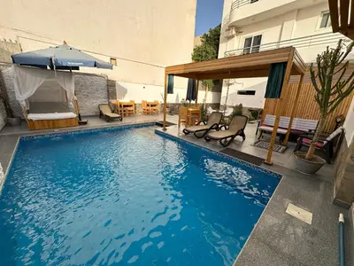 a swimming pool with chairs and an umbrella next to a building at Nile Spirit Sunset in Luxor