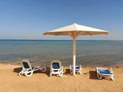 two chairs and an umbrella on a beach at Selena bay resort in Hurghada