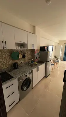 a kitchen with white cabinets and a washer at Luxury studio with beach in Hurghada