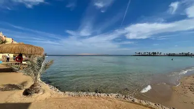 a beach with a straw umbrella and the ocean at Luxury studio with beach in Hurghada