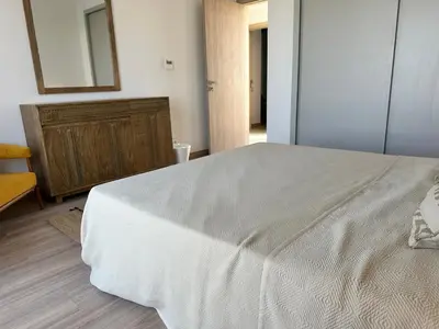 a bedroom with a white bed and a wooden dresser at Fanadir Marina Vista in Hurghada