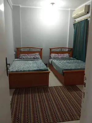 two beds in a room with a door open at شقه الزناتى مطله على النيل in Luxor
