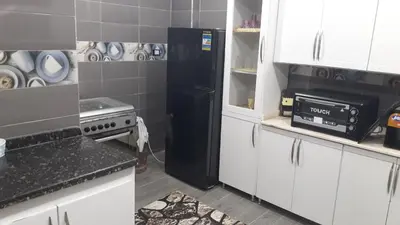 a kitchen with a black refrigerator and white cabinets at الاقصر البر الغربي امام معبد هابو in Al Aqālitah