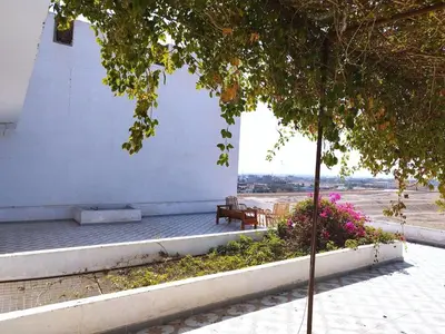 a bench next to a white building with flowers at Gabawy Garden in ‘Ezbet Abu Ḥabashi