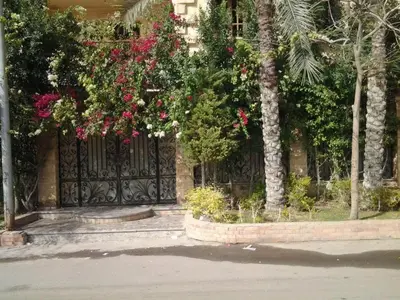 a building with a gate with pink flowers on it at cozy penthouse in New Cairo in Kharga