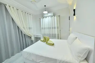 a white bedroom with two stuffed animals sitting on a bed at Villa Luna Simone in Al Karnak