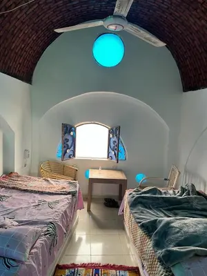a bedroom with two beds and a ceiling fan at Nubia House Nile View in Nag` el-Ramla