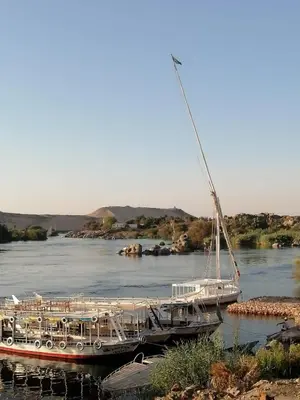 two boats are docked on a river at Nubia House Nile View in Nag` el-Ramla