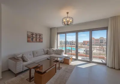 a living room with a couch and a large window at Sophisticated 1BR 1,5 Bath Duplex - Kamaran El Gouna, Pool View & Access in Hurghada