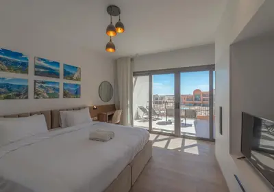 a bedroom with a large white bed and a television at Sophisticated 1BR 1,5 Bath Duplex - Kamaran El Gouna, Pool View & Access in Hurghada