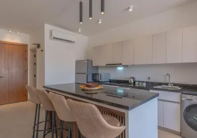 a kitchen with a island with bar stools at Sophisticated 1BR 1,5 Bath Duplex - Kamaran El Gouna, Pool View & Access in Hurghada