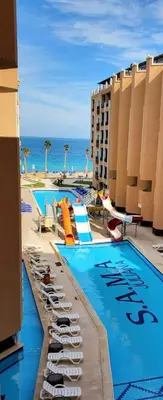 a hotel swimming pool with chairs and the ocean at Seaview 2 Bedroom Private Deluxe Condo at Juliana Beach Resort B2-09 in Hurghada
